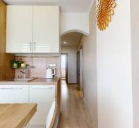 Vyššie už je nebo. 3izbový byt po kompletnej rekonštrukcii  - Kuchynská linka s bielymi skrinkami a podlahou s dreveným dekorom v 3-izbovom byte.