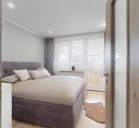 Vyššie už je nebo. 3izbový byt po kompletnej rekonštrukcii  - Spálňa v 3-izbovom byte s posteľou, závesmi a podlahou s dreveným dekorom.