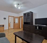 AstonReal:  predaj 2-izbový byt 54 m2, Poprad - Západ, Komenského - Obývacia izba s tmavým nábytkom a podlahou s dreveným dekorom v 2-izbovom byte.