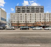 KOMPLETNE ZARIADENÝ 2-IZB. BYT,BALKÓN + PIVNICA,BUDATÍNSKA – PETRŽALKA - Budova na ulici Budatinská v Bratislave - Petržalke s autami zaparkovanými pred ňou.