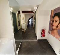 Prenájom obchodného priestoru, Hauptstraße, Hauptstraße, Eisenstadt - Chodba obchodných priestorov s plakátom, podlahou s dreveným dekorom a hasiacim prístrojom.