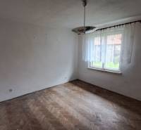 PREDAJ: Rodinný dom Kalameny s pozemkom 1.789m2 - Prázdna miestnosť s oknom, lustrom a podlahou s dreveným dekorom v rodinnom dome.