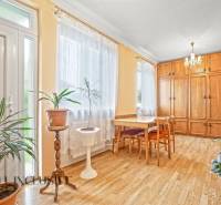 NA PREDAJ 4-IZBOVÝ RD NA VEĽKOM POZEMKU, VRAKÚŇ - Jasná izba v rodinnom dome so skriňami, stolom a kvetmi, s podlahou s dreveným dekorom.