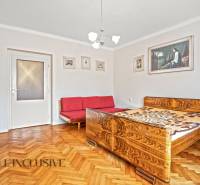 NA PREDAJ 4-IZBOVÝ RD NA VEĽKOM POZEMKU, VRAKÚŇ - Spálňa v rodinnom dome s posteľou, červenou pohovkou a podlahou s dreveným dekorom.