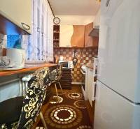 Predaj 2-izbového bytu v Krásne nad Kysucou - Kuchyňa v 2-izbovom byte s dekoratívnym kobercom, stolčekmi a dlaždicovou stenou.