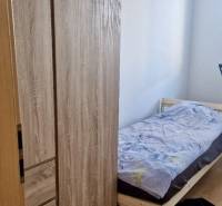 Prenájom 3 - izbový byt Bratislava - Petržalka - Jednolôžková posteľ a skriňa s podlahou s dreveným dekorom v 3-izbovom byte.