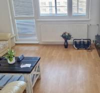 Prenájom 3 - izbový byt Bratislava - Petržalka - Obývacia izba v 3-izbovom byte s podlahou s dreveným dekorom a pohodlnou sedačkou.