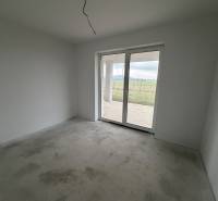 Novostavba rodinný dom Práznovce - Izba v rodinnom dome so sivou podlahou a veľkými oknami smerom do dvora.