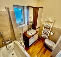 ,Predaj 4 izbový byt, 99 m2 + 30 m2 terasa,3 x parkovanie, BA II - Kúpeľňa so sprchou nad vaňou, umývadlom a podlahou s dreveným dekorom v 4-izbovom byte.