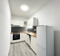 NA PRENÁJOM! Veľkometrážny 56m2 1i byt, Veľkomoravská, Trenčín - Kuchyňa v 1-izbovom byte s čiernym obkladom a podlahou s dreveným dekorom.