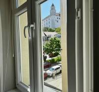 Prenájom veľkého luxusného 2izb bytu pri Bratislavskom hrade - Výhľad z 2-izbového bytu na Bratislavský hrad cez okno s bielym rámom.