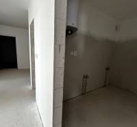 Predaj 3-izbového bytu len 15 minút od Bratislavy  - Nezariadený priestor v 3-izbovom byte s namontovaným bojlerom bez podlahy s dreveným dekorom.