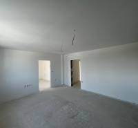 Predaj 3-izbového bytu len 15 minút od Bratislavy  - Svetlá priestranná miestnosť v 3-izbovom byte s holými stenami a prípravou na podlahu.