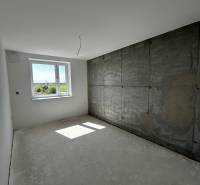 Predaj 3-izbového bytu len 15 minút od Bratislavy  - Svetlá izba s betónovou stenou a oknom v 3-izbovom byte.