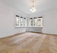 Predaj 4-izbový byt, 102m2, terasa 50m2, Bratislava-centrum, Gorkého - Izba v 4-izbovom byte so svetlom lustrom, podlahou s dreveným dekorom a veľkými oknami.