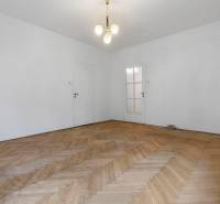 Predaj 4-izbový byt, 102m2, terasa 50m2, Bratislava-centrum, Gorkého - Priestranná miestnosť s bielymi stenami a podlahou s dreveným dekorom v 4-izbovom byte.