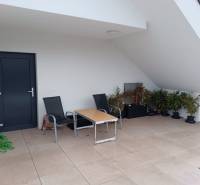 Štýlový 2-izbový byt s exkluzívnou terasou 102 m²  - Balkón v 2-izbovom byte s terasou, stoličkami a rastlinami.