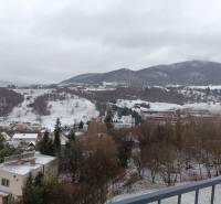 Štýlový 2-izbový byt s exkluzívnou terasou 102 m²  - Zasnežená krajina v Nová Baňa z ulice Pod sekvojou pri pohľade zo zimného balkóna.