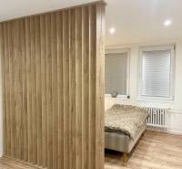 | Predaj 1-izbového bytu – Račianska, Bratislava - Spálňa s deliacou drevenou stenou a podlahou s dreveným dekorom v 1-izbovom byte.