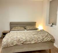 | Predaj 1-izbového bytu – Račianska, Bratislava - Spálňa v 1-izbovom byte s manželskou posteľou a podlahou s dreveným dekorom.