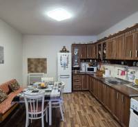 3 IZBOVÝ RODINNÝ DOM S GARÁŽOU, VEĽKÉ OZOROVCE - Kuchyňa v rodinnom dome s drevenými skrinkami a podlahou s dreveným dekorom.