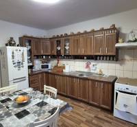 3 IZBOVÝ RODINNÝ DOM S GARÁŽOU, VEĽKÉ OZOROVCE - Kuchyňa v rodinnom dome s kuchynskou linkou, jedálenským stolom a podlahou s dreveným dekorom.