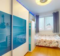 4i byt s atmosférou domu, terasou a parkovaním | Vrakuňa, 129m2 - Izba v 4-izbovom byte s posteľou, písacím stolom a podlahou s dreveným dekorom.