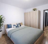 REZERVOVANÉ Prenájom  2-izbového bytu v Petržalke - Spálňa v 2-izbovom byte s posteľou, skriňou a podlahou s dreveným dekorom.