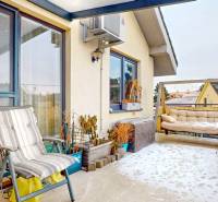 4i byt s atmosférou domu, terasou a parkovaním | Vrakuňa, 129m2 - Zasnežená terasa 4-izbového bytu s kreslom, rastlinami a pohovkou.