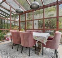 Nadštandardná 6-izbová vila v prominentnej lokalite - Jedáleň vo Vile s presklenými stenami, ružové kreslá, stôl a kvetinové aranžmány.