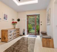 Nadštandardná 6-izbová vila v prominentnej lokalite - Interiér vily s drevenou komodou, kvetinovou dekoráciou a presklenými dverami do záhrady.