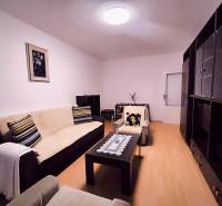 ‼️  PRENÁJOM  - 2 IZBOVÉHO BYTU, PARTIZÁNSKE SÍDLISKO ŠÍPOK ‼️ - Obývacia izba so sedačkou, dekoratívnymi vankúšmi a podlahou s dreveným dekorom v 2-izbovom byte.