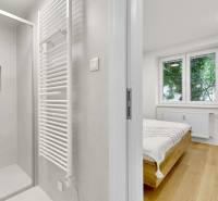 I Na predaj zrekonštruovaný 4i byt v Ružinove, Miletičova - Kúpeľňa so sprchovým kútom a spálňa v 4-izbovom byte, podlaha s dreveným dekorom.