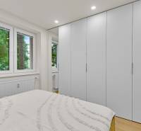 I Na predaj zrekonštruovaný 4i byt v Ružinove, Miletičova - Spálňa v 4-izbovom byte s bielymi vstavanými skriňami a podlahou s dreveným dekorom.