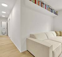 I Na predaj zrekonštruovaný 4i byt v Ružinove, Miletičova - Obývačka s krémovou sedačkou a bielou policou, podlaha s dreveným dekorom v 4-izbovom byte.