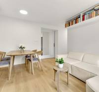 I Na predaj zrekonštruovaný 4i byt v Ružinove, Miletičova - Obývačka so svetlou sedačkou, stolom a podlahou s dreveným dekorom v 4-izbovom byte.