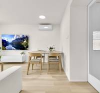 I Na predaj zrekonštruovaný 4i byt v Ružinove, Miletičova - Obývačka v 4-izbovom byte s podlahou s dreveným dekorom, televízorom a kvetmi.