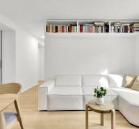 I Na predaj zrekonštruovaný 4i byt v Ružinove, Miletičova - Obývacia izba s bielou pohovkou, dreveným stolíkom a poličkou plnou kníh v 4-izbovom byte.