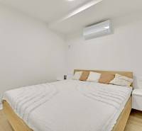 I Na predaj zrekonštruovaný 4i byt v Ružinove, Miletičova - Svetlá spálňa s klimatizáciou a posteľou vedľa nočného stolíka v 4-izbovom byte.