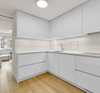 I Na predaj zrekonštruovaný 4i byt v Ružinove, Miletičova - Kuchyňa v 4-izbovom byte s bielymi skrinkami a podlahou s dreveným dekorom.