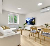 I Na predaj zrekonštruovaný 4i byt v Ružinove, Miletičova - Obývacia izba so sedačkou, jedálenským stolom a podlahou s dreveným dekorom v 4-izbovom byte.