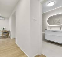 I Na predaj zrekonštruovaný 4i byt v Ružinove, Miletičova - Chodba v 4-izbovom byte s podlahou s dreveným dekorom, pohľad do kúpeľne.