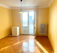 Predáj 1i čiastočne zrekonštruovaný byt s loggiou - Izba s podlahou s dreveným dekorom, žltými stenami a balkónom v 1-izbovom byte.