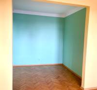 Predáj 1i čiastočne zrekonštruovaný byt s loggiou - Izba v 1-izbovom byte s podlahou s dreveným dekorom a svetlými stenami.