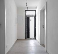 I PREDAJ novostavba 4i rodinného domu s terasou a záhradkou - Vstupná hala v rodinnom dome s bielymi stenami a dlažbou.