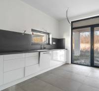 I PREDAJ novostavba 4i rodinného domu s terasou a záhradkou - Kuchyňa v rodinnom dome s bielymi skrinkami, čiernou pracovnou doskou a veľkým oknom.