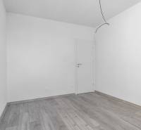 I PREDAJ novostavba 4i rodinného domu s terasou a záhradkou - Prázdna miestnosť v rodinnom dome s podlahou s dreveným dekorom a bielymi stenami.