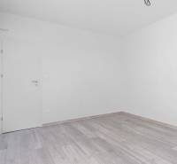 I PREDAJ novostavba 4i rodinného domu s terasou a záhradkou - Prázdna miestnosť s bielymi stenami a podlahou s dreveným dekorom v rodinnom dome.