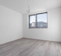 I PREDAJ novostavba 4i rodinného domu s terasou a záhradkou - Prázdna izba s podlahou s dreveným dekorom a veľkým oknom v rodinnom dome.