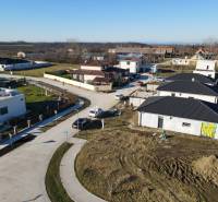 I NA PREDAJ 4i rodinný dom s veľkým pozemkom v Galante - Rodinné domy v Galante s neúplne dokončenou záhradou, viditeľné chodníky a autá na ceste.